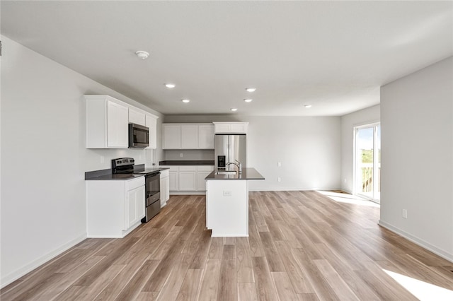 kitchen with stainless steel appliances, white cabinetry, a kitchen island with sink, and light hardwood / wood-style flooring