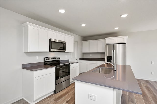 kitchen featuring stainless steel appliances, white cabinetry, a center island with sink, and sink