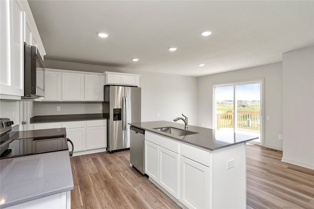 kitchen with white cabinetry, sink, stainless steel appliances, an island with sink, and light hardwood / wood-style floors