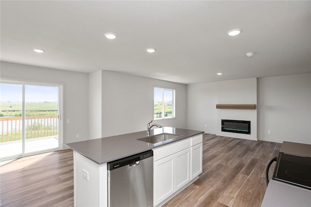 kitchen featuring stainless steel dishwasher, a kitchen island with sink, sink, wood-type flooring, and white cabinets