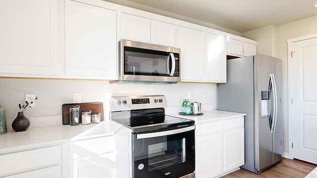 kitchen with light hardwood / wood-style flooring, appliances with stainless steel finishes, and white cabinets