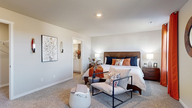 bedroom featuring light carpet, connected bathroom, a walk in closet, and a closet