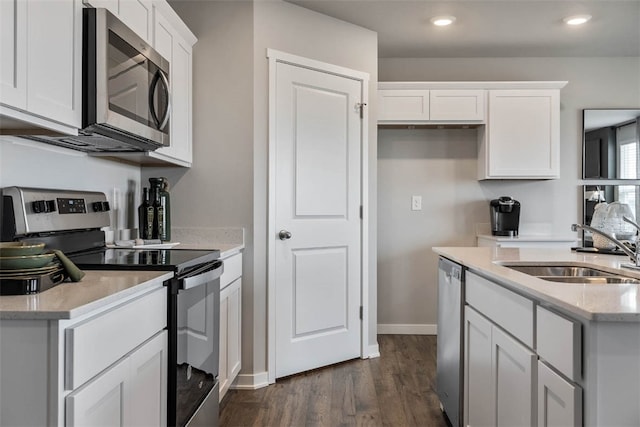 kitchen with dark hardwood / wood-style floors, stainless steel appliances, sink, light stone counters, and white cabinets