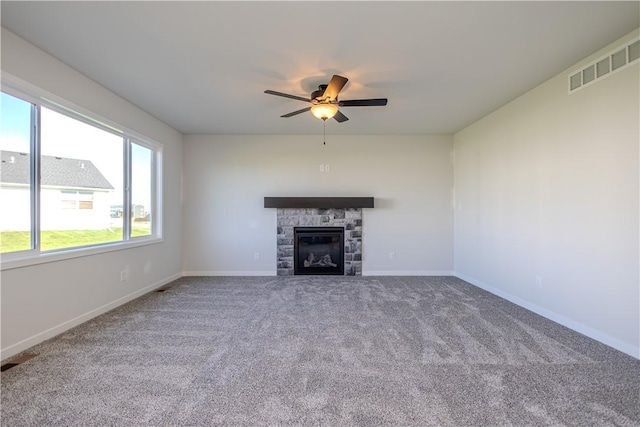 unfurnished living room featuring carpet flooring, ceiling fan, and a stone fireplace