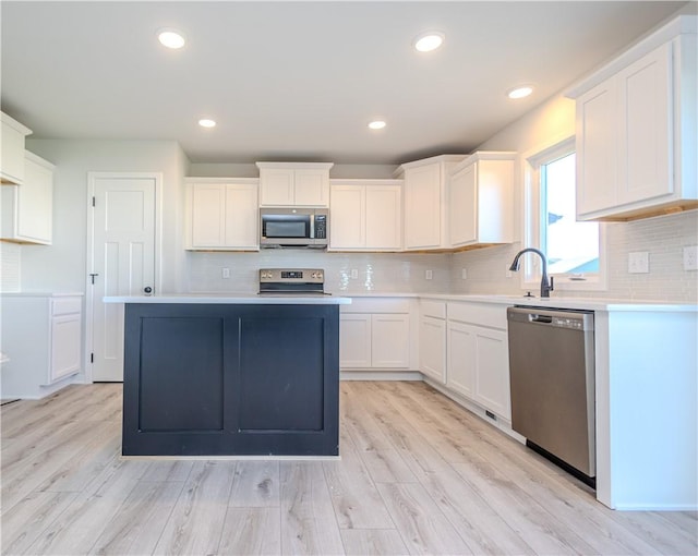 kitchen with white cabinets, a center island, light hardwood / wood-style floors, and stainless steel appliances