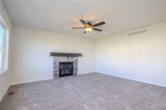 unfurnished living room featuring carpet floors, a stone fireplace, and plenty of natural light