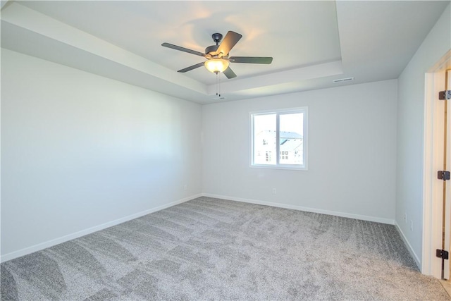 unfurnished room featuring light colored carpet, a raised ceiling, and ceiling fan