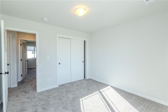 unfurnished bedroom featuring light colored carpet and a closet