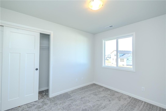 unfurnished bedroom with light carpet and a closet