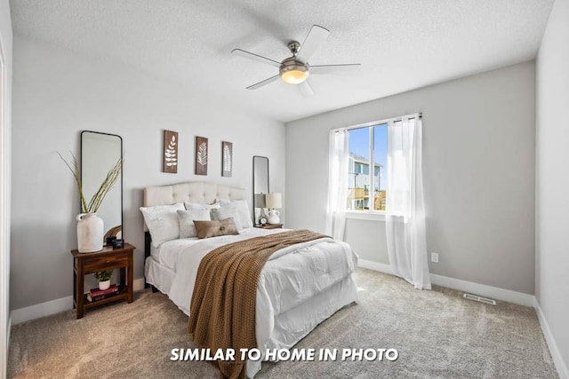 bedroom with ceiling fan, light carpet, and a textured ceiling