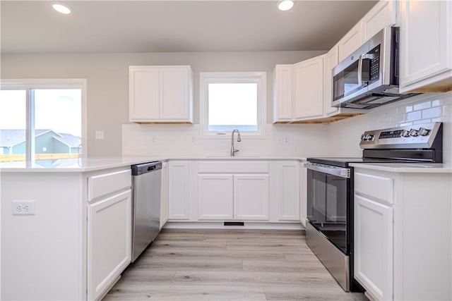 kitchen with sink, appliances with stainless steel finishes, plenty of natural light, and white cabinetry