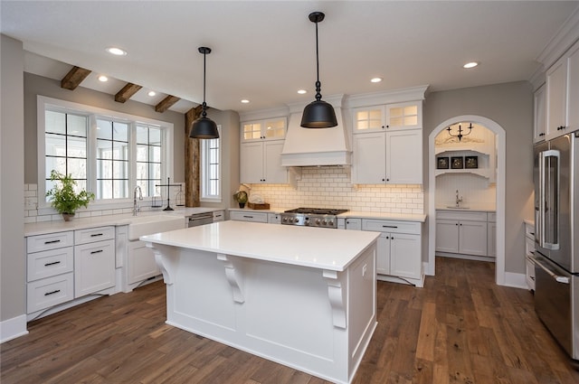 kitchen with dark hardwood / wood-style floors, a kitchen island, beamed ceiling, stainless steel appliances, and premium range hood