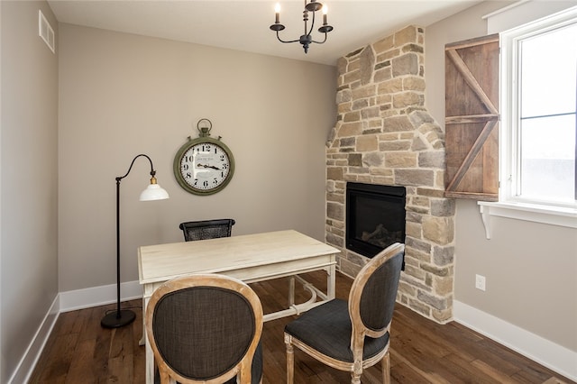 office with dark hardwood / wood-style floors, an inviting chandelier, and a stone fireplace