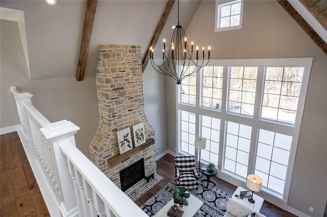 living room with a notable chandelier, dark hardwood / wood-style floors, and beamed ceiling