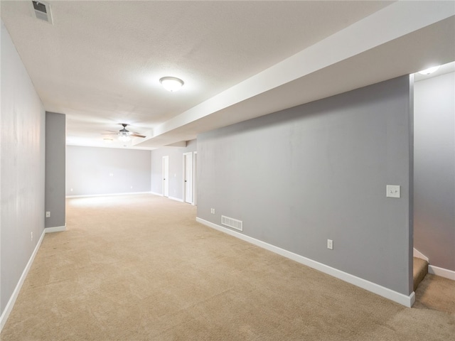 basement featuring ceiling fan and light colored carpet