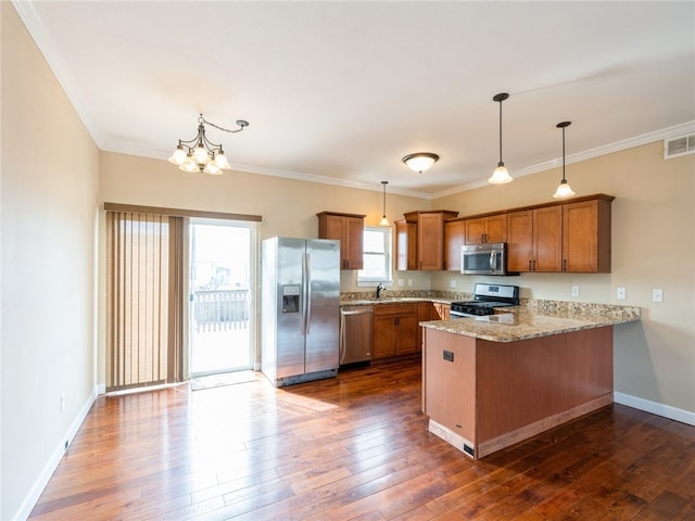 kitchen featuring kitchen peninsula, dark wood-type flooring, light stone counters, hanging light fixtures, and appliances with stainless steel finishes