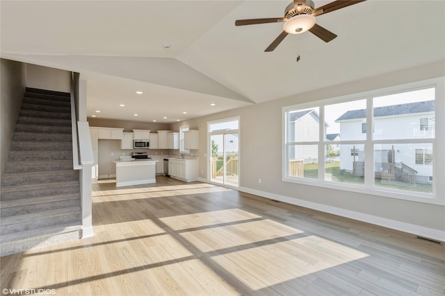 unfurnished living room featuring ceiling fan, vaulted ceiling, and light hardwood / wood-style flooring