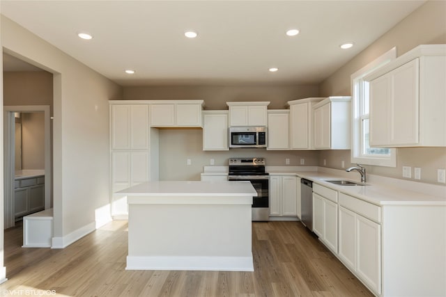 kitchen with a kitchen island, sink, appliances with stainless steel finishes, and white cabinets