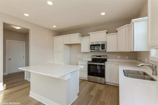 kitchen featuring light hardwood / wood-style flooring, stainless steel appliances, white cabinetry, sink, and a kitchen island