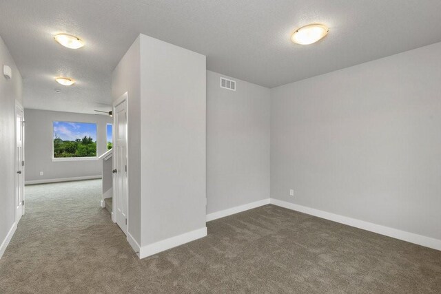 carpeted empty room with a textured ceiling