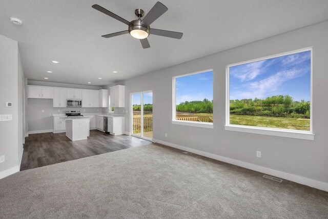 unfurnished living room with ceiling fan and dark carpet