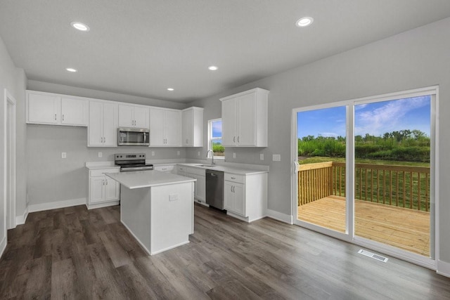 kitchen featuring stainless steel appliances, dark hardwood / wood-style floors, a center island, and white cabinets