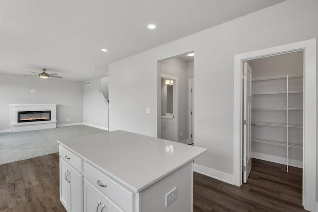 kitchen featuring white cabinetry, dark hardwood / wood-style flooring, a center island, and ceiling fan