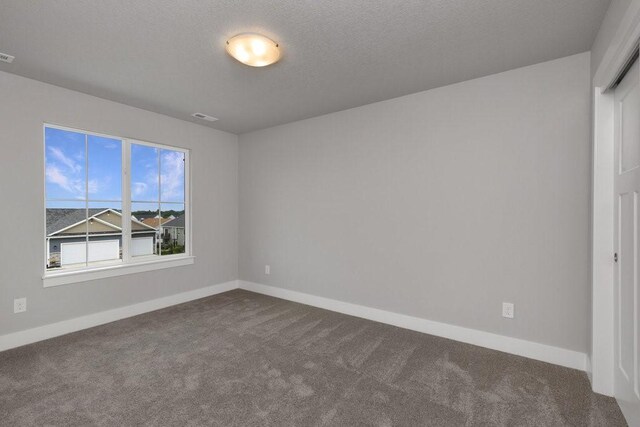 carpeted spare room with a textured ceiling