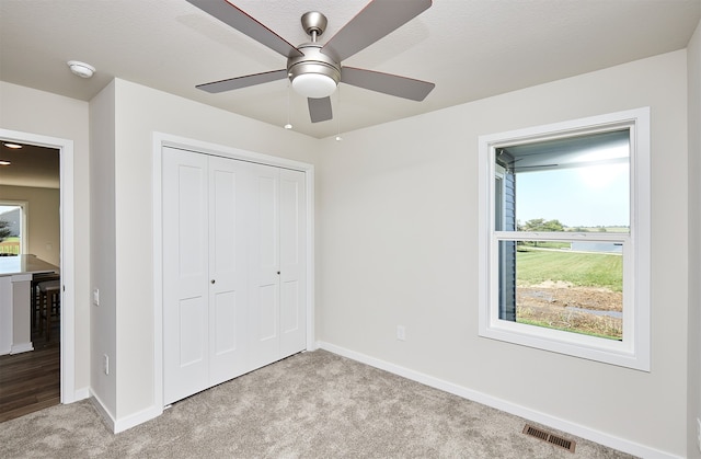 unfurnished bedroom with light carpet, a textured ceiling, ceiling fan, and a closet