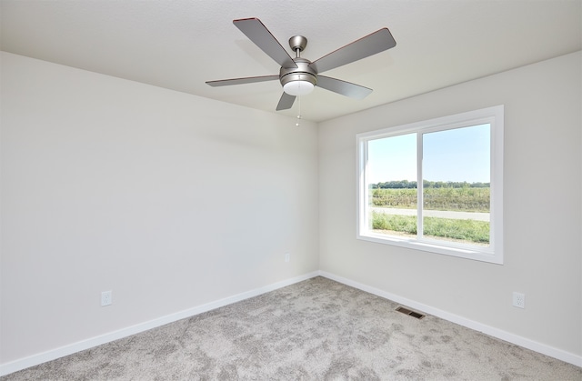 carpeted spare room featuring ceiling fan