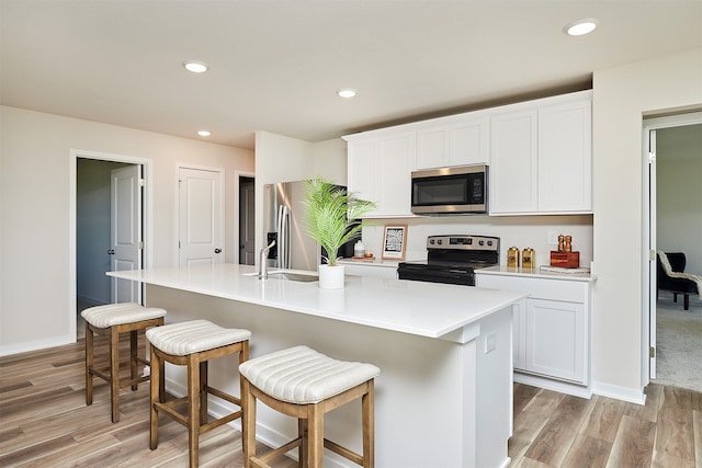 kitchen featuring white cabinets, stainless steel appliances, and an island with sink