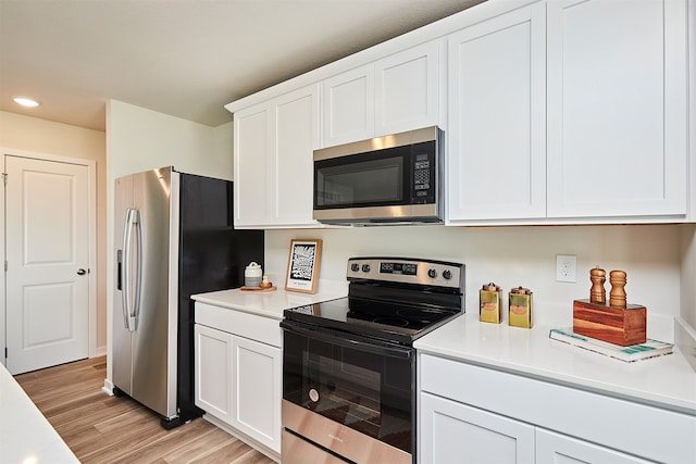 kitchen featuring light wood-type flooring, appliances with stainless steel finishes, and white cabinets