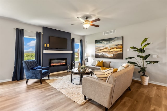 living area with a wealth of natural light, a large fireplace, and wood finished floors