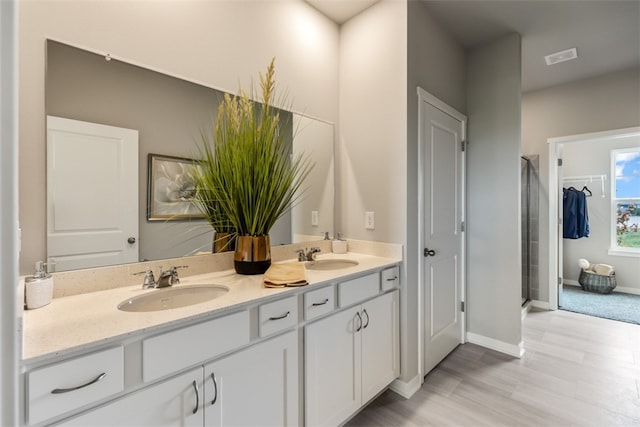 bathroom featuring double vanity, baseboards, a shower stall, and a sink