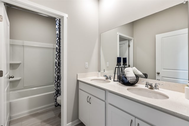 full bathroom featuring double vanity, toilet, shower / tub combo with curtain, and a sink