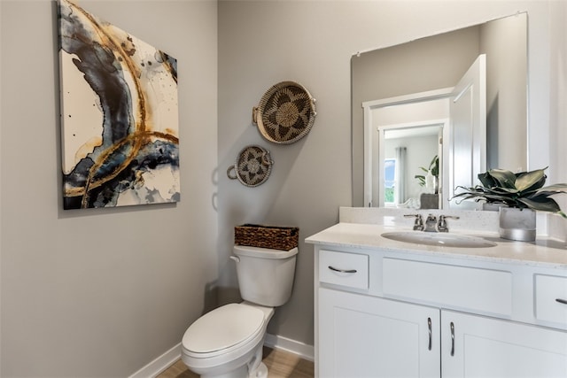 half bath with toilet, vanity, and baseboards