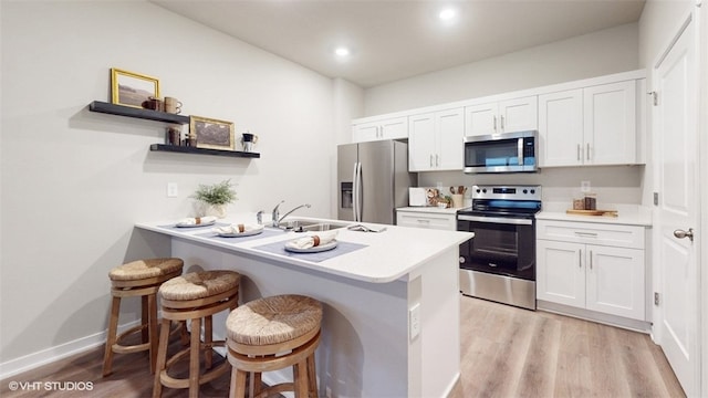 kitchen featuring a breakfast bar, sink, appliances with stainless steel finishes, kitchen peninsula, and white cabinets