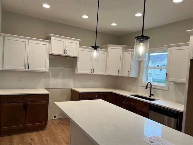 kitchen with light hardwood / wood-style floors, hanging light fixtures, stainless steel dishwasher, and tasteful backsplash