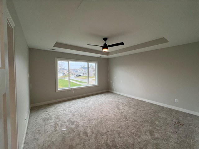 carpeted empty room featuring a raised ceiling and ceiling fan