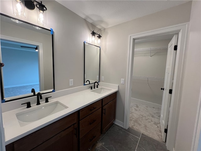 bathroom with oversized vanity, a textured ceiling, double sink, and tile flooring