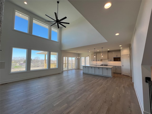 unfurnished living room with wood-type flooring, ceiling fan with notable chandelier, and plenty of natural light