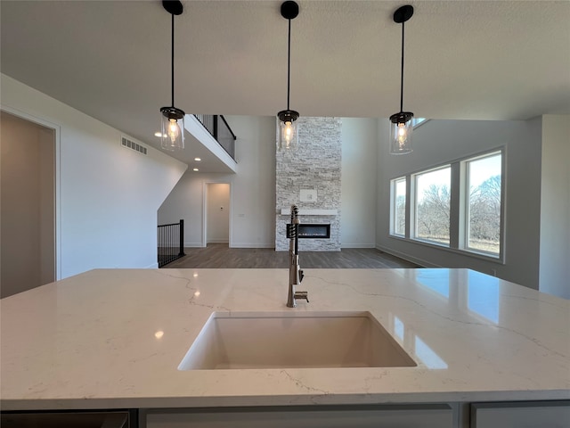 kitchen with wood-type flooring, decorative light fixtures, and light stone countertops