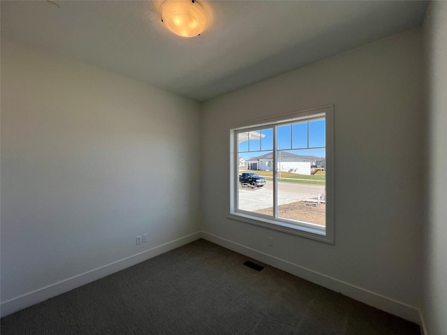 unfurnished room with dark colored carpet