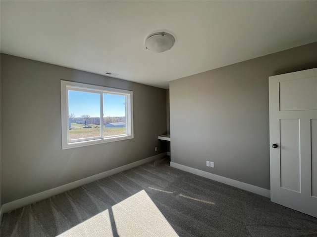 unfurnished room with dark colored carpet