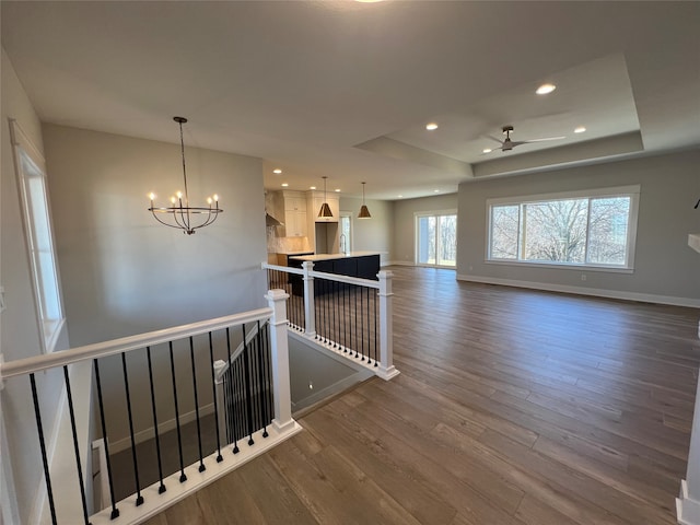 interior space featuring ceiling fan with notable chandelier, wood-type flooring, and sink