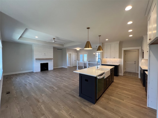 kitchen featuring light hardwood / wood-style flooring, an island with sink, and white cabinets