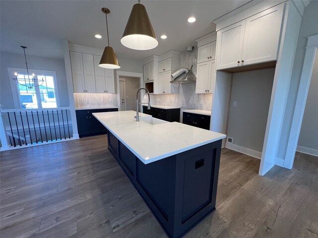 kitchen with pendant lighting, an island with sink, and white cabinets