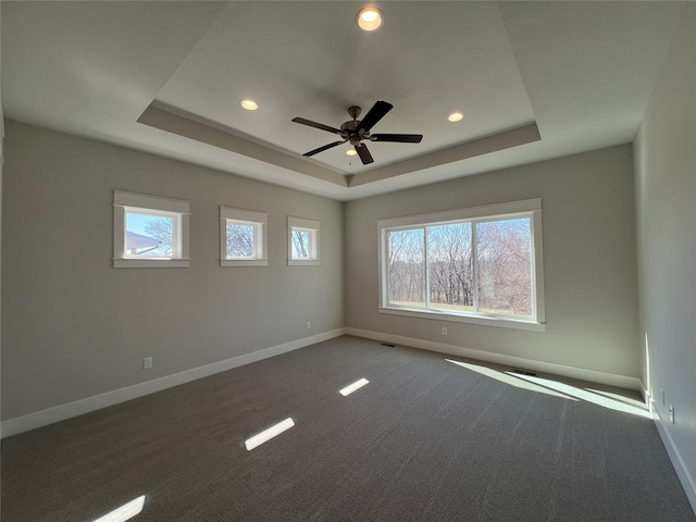 carpeted spare room featuring ceiling fan and a raised ceiling