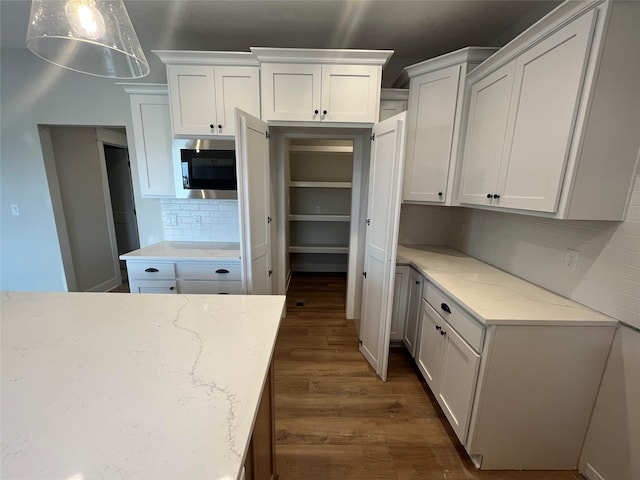 kitchen featuring dark wood-type flooring, white cabinetry, and backsplash