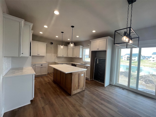 kitchen featuring white cabinetry, sink, a kitchen island, pendant lighting, and dark hardwood / wood-style flooring